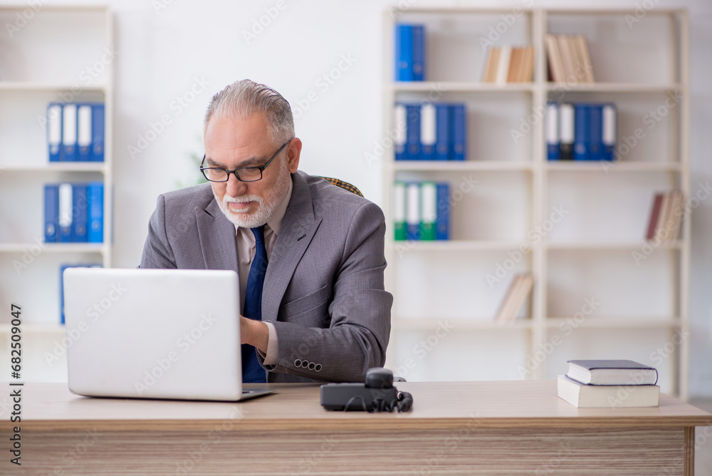 Old male employee working in the office Old male employee working in the office