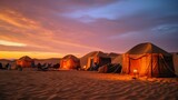 A nomadic desert campsite with colorful tents amidst the golden sand dunes.