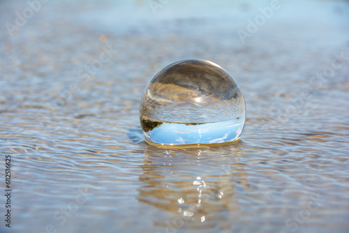 Beach and sea reflected in a sphere lying in the water