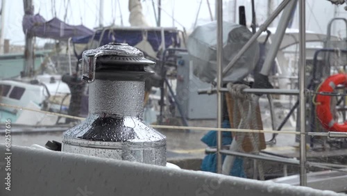Drops of autumn rain break on the winch of a sailing yacht in the harbor. Slow motion.