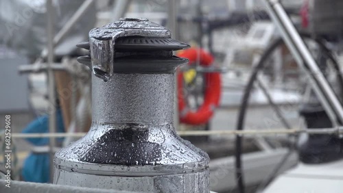 Drops of autumn rain break on the winch of a sailing yacht in the harbor. Slow motion.