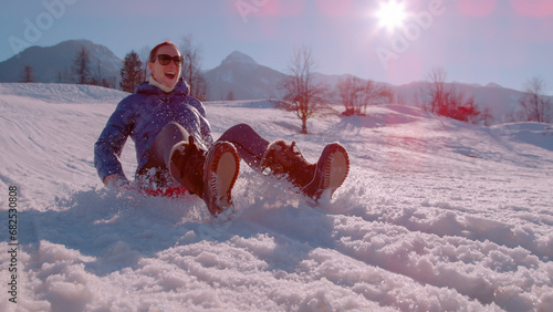 Fotografie CLOSE UP, LENS FLARE: Sunny winter day with a lady sledding down the snowy hill