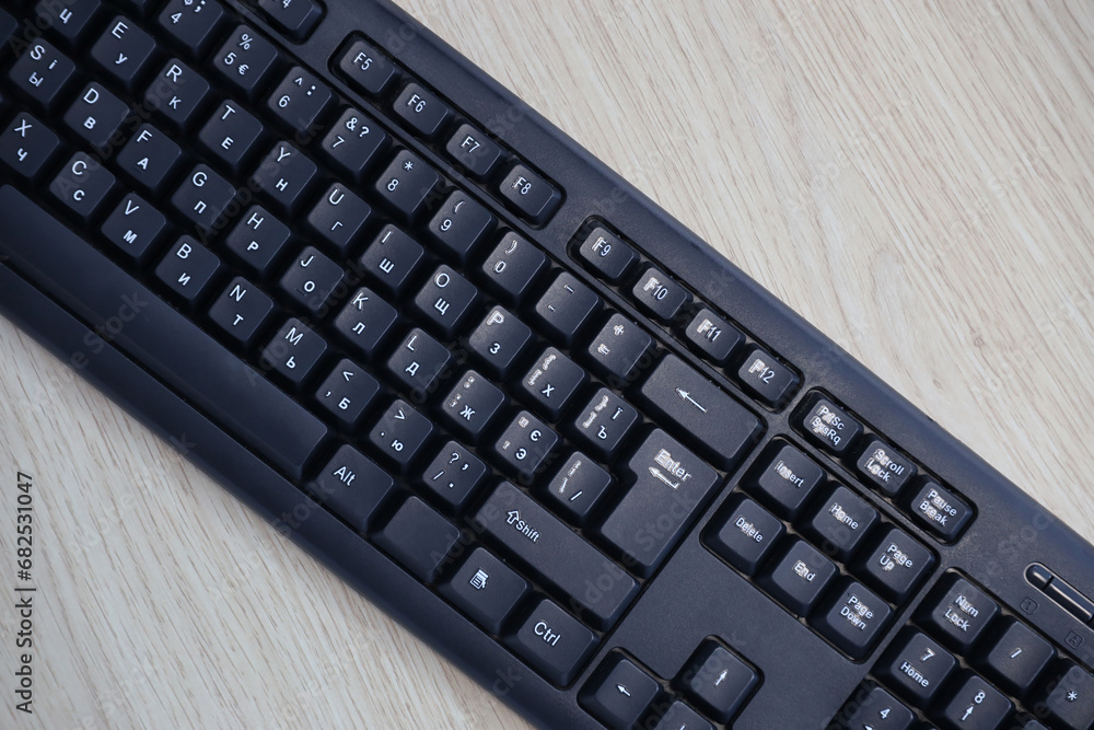 Small compact black gaming computer keyboard on a table made of wooden pine boards. Wireless keyboard with mechanical switches for gadgets and computer. Copy space Small compact black gaming computer keyboard on a table made of wooden pine boards. Wireless keyboard with mechanical switches for gadgets and computer. Copy space