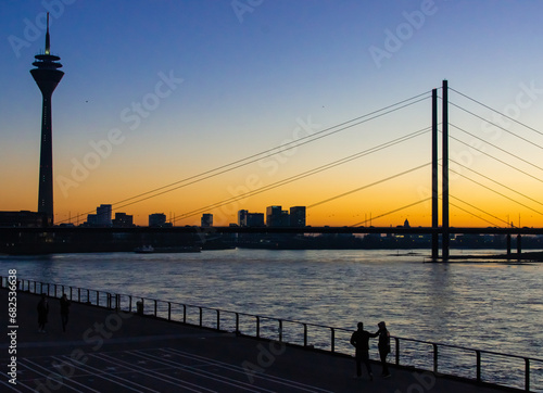 Bridge over the river Rhine in Dusseldorf. It is sunset with orange light at the horizon and a blue sky. photo