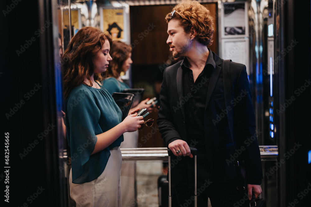 Business couple arriving at hotel. They are about to have a meeting with investors. Business people discussing in elevator. Business couple arriving at hotel. They are about to have a meeting with investors. Business people discussing in elevator.