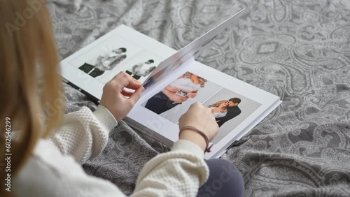 A teen girl flips through a photo book with photos of her dad and pregnant mom. photo
