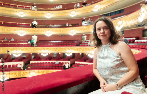 Young woman after watching performance poses in auditorium balcony of liceu theater photo