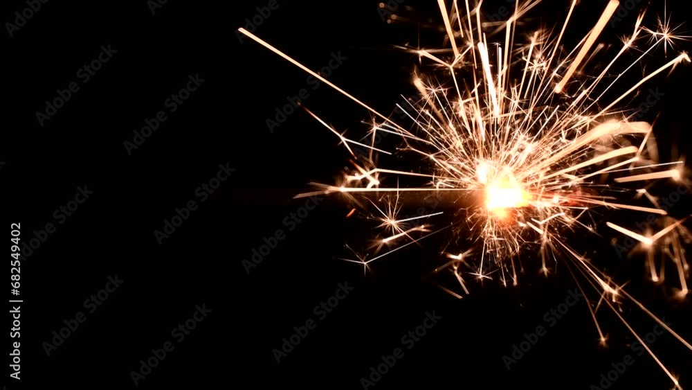 close up of burning sparkler against black background close up of burning sparkler against black background