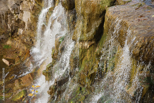 Beautiful waterfall between large rocks in the autumn forest. Sofievskiy park in Uman, Ukraine