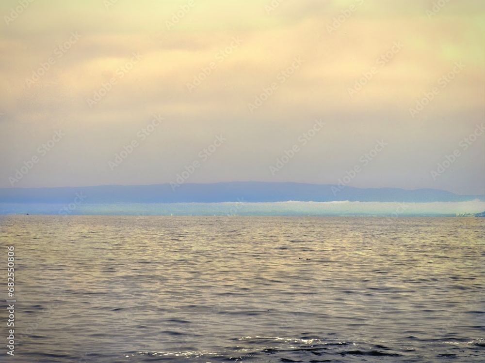 Obraz premium A tranquil and minimal seascape, toned in pale golden yellow with a strip of blue on the horizon.
