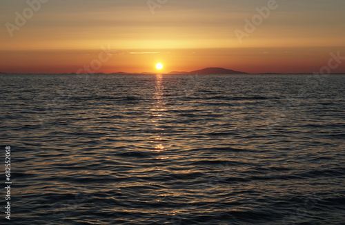 Pale and pastel colors of sea surface with waves and sundown on the horizon