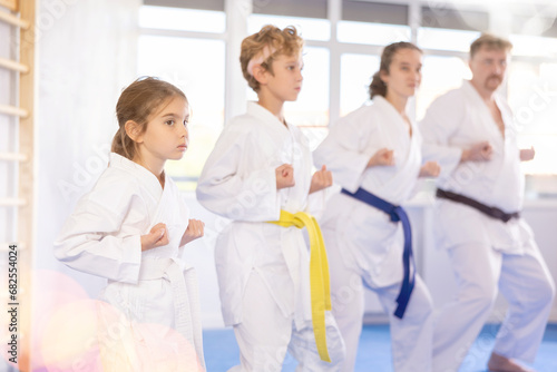 Parents with children athletes starting position and studying repeating sequence of punches and painful techniques in karate kata technique. Oriental martial arts, training and obtaining black belt photo