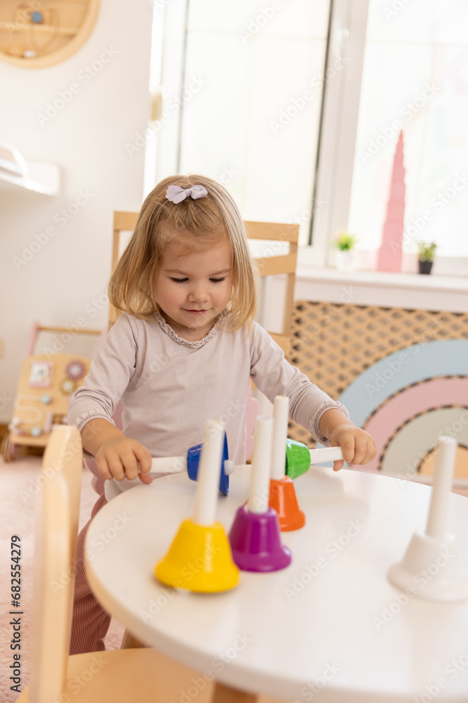 Toddler girl playing with bells in the kindergarten Toddler girl playing with bells in the kindergarten