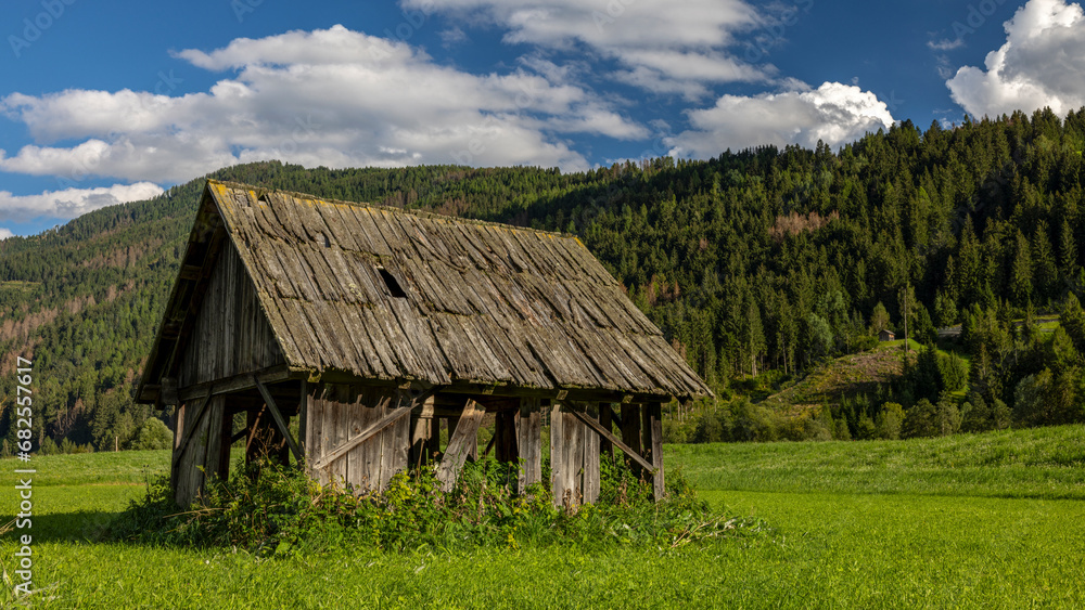 eine alte Bauernhütte auf einer grünen Wiese