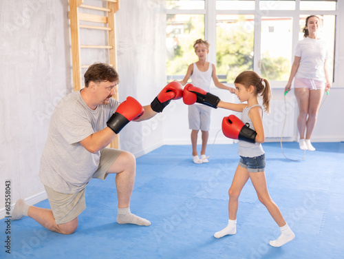 Father and daughter wearing boxing gloves train boxing punches in studio
