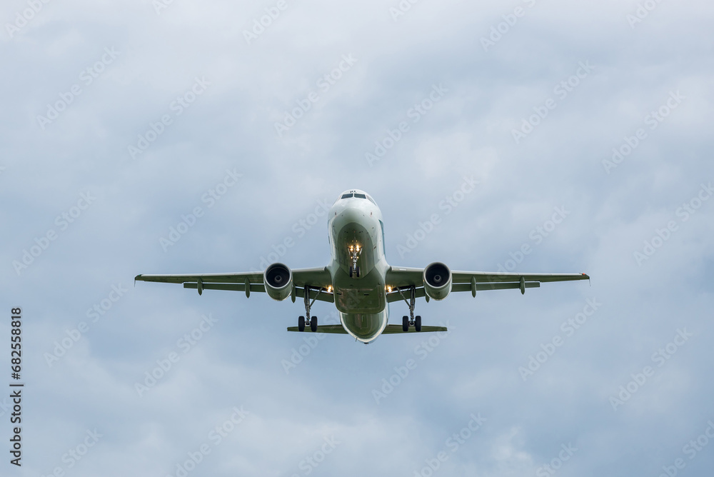 Passenger jet plane coming in for a landing. View from below. Jet commercial aviation. The plane flies towards the photographer Passenger jet plane coming in for a landing. View from below. Jet commercial aviation. The plane flies towards the photographer