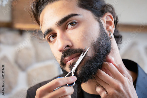 uomo che si taglia la barba con forbice  photo