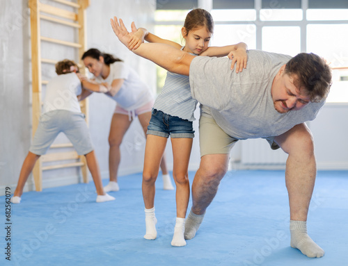 Father and daughter training self-defense techniques in studio