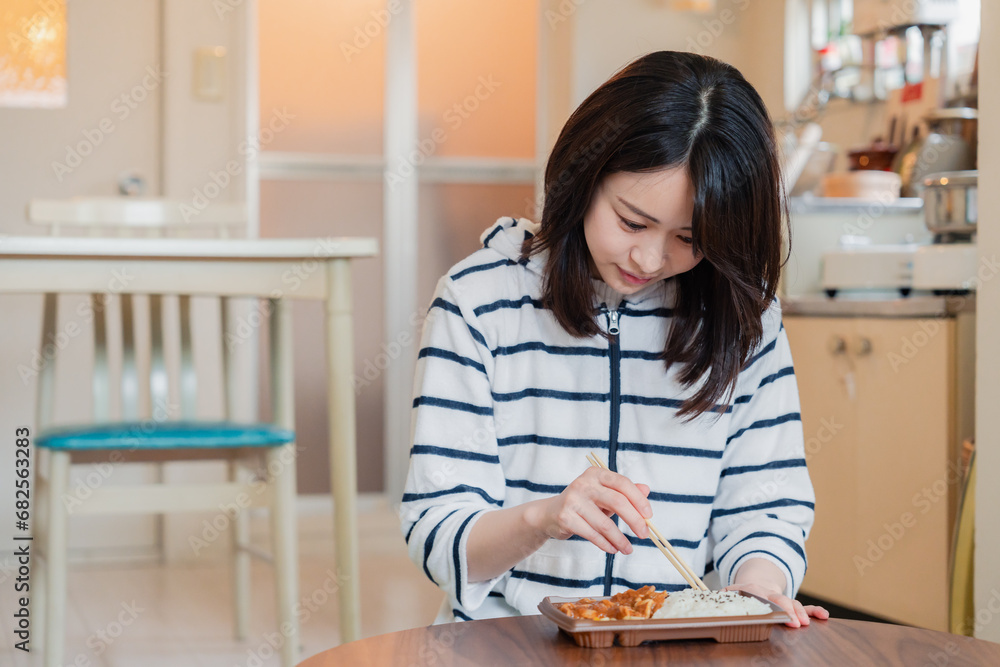 家でひとりでコンビニ弁当を食べる若い女性 家でひとりでコンビニ弁当を食べる若い女性