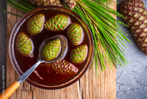 Young pine cones jam in glass bowl on wooden board. Delicious jam with the little pine cones.