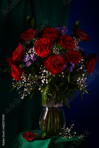 Red roses, white gypsophila and lilac asters in a glass vase.