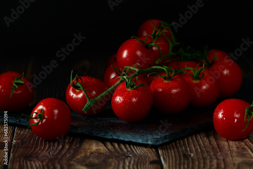 Tomatoes lying on a pile on top of each other on a black slate.