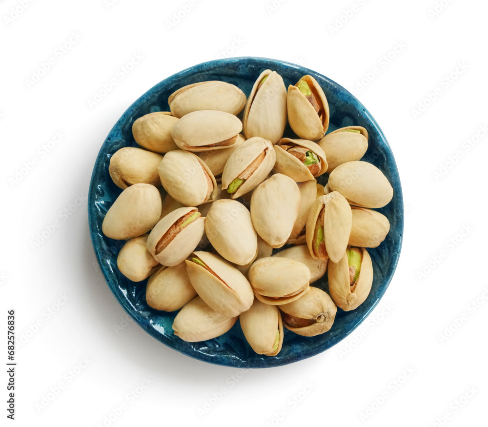 Bowl or dish of raw organic pistachios that are salted and roasted on a white background Bowl or dish of raw organic pistachios that are salted and roasted on a white background