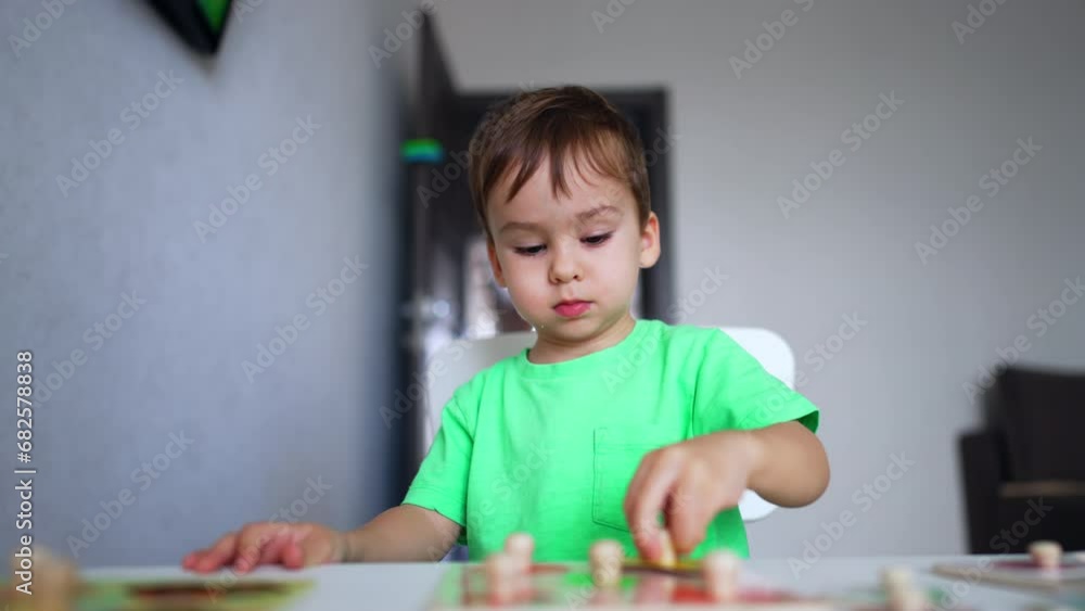Beautiful Caucasian toddler is focused on his game. Baby boy is carefully looking for the necessary particle of a puzzle. Beautiful Caucasian toddler is focused on his game. Baby boy is carefully looking for the necessary particle of a puzzle.