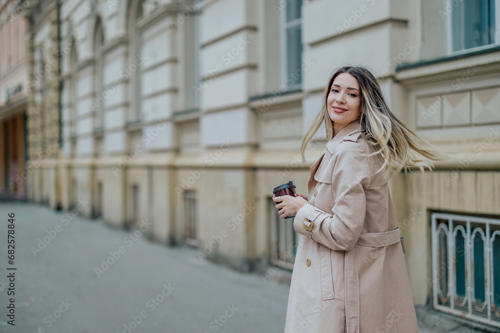 Woman drinking coffee takeaway and swinging her hair while walking outside