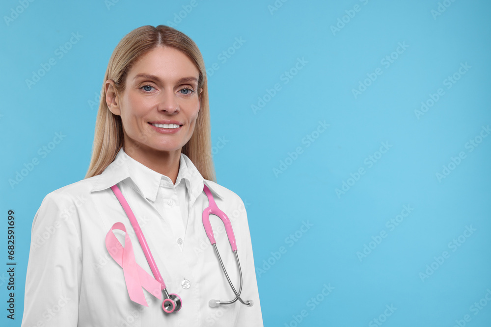 Doctor with pink ribbon and stethoscope on light blue background, space for text. Breast cancer awareness Doctor with pink ribbon and stethoscope on light blue background, space for text. Breast cancer awareness