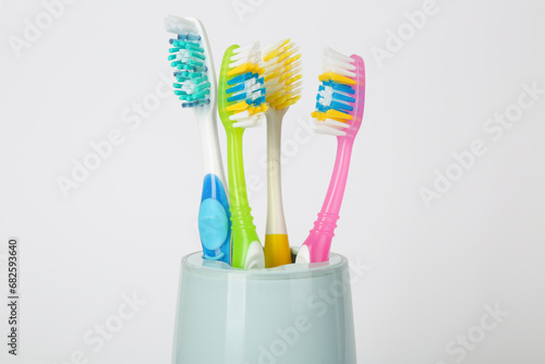 Different toothbrushes in holder on light grey background  closeup