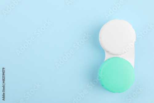 Case with color contact lenses on light blue background, top view. Space for text