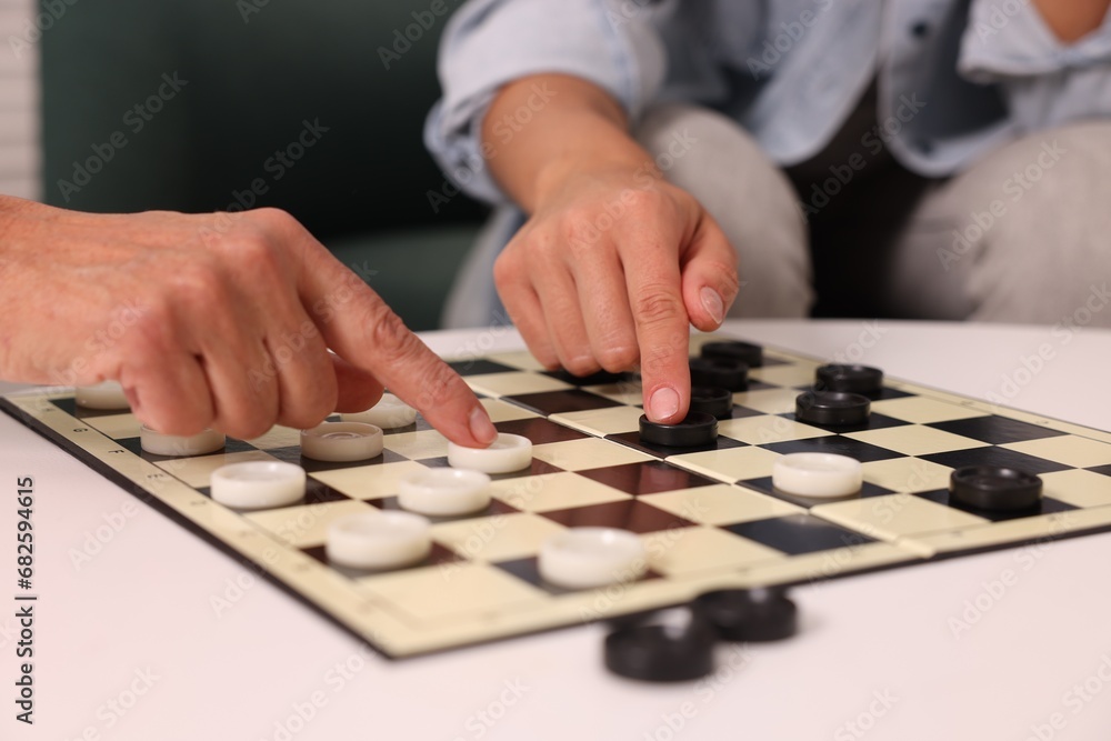 Naklejka premium Women playing checkers at white table, closeup