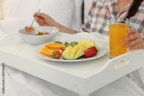 Young woman having breakfast on bed at home  closeup