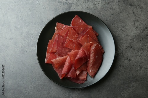 Plate with tasty bresaola on grey table, top view photo