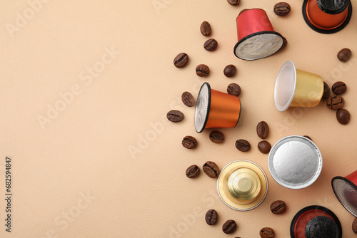 Many coffee capsules and beans on beige background, flat lay. Space for text photo