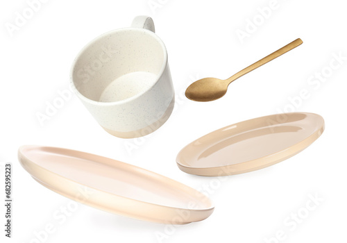 Clean plates, spoon and cup falling on white background