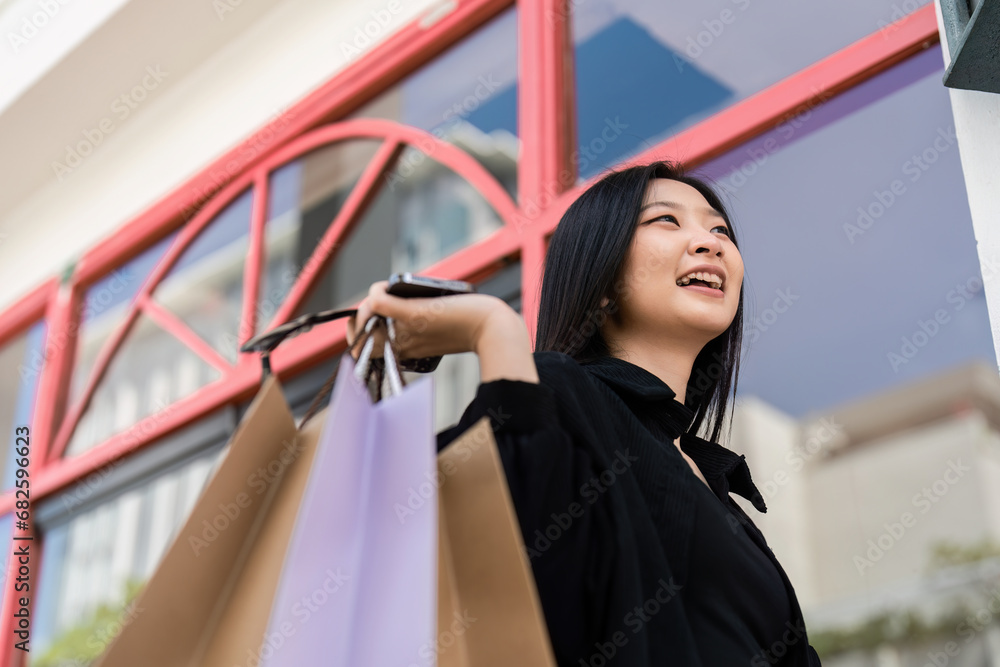 Young asian woman in shopping. Fashion woman in black with shopping bag walking around the city after shopping. Black friday