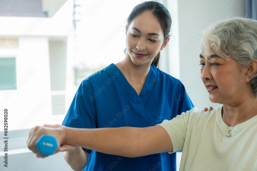 Obraz premium A young Asian nurse at a nursing home takes care of a senior woman. The attending physician provides physical therapy services for elderly patients to exercise for their health.