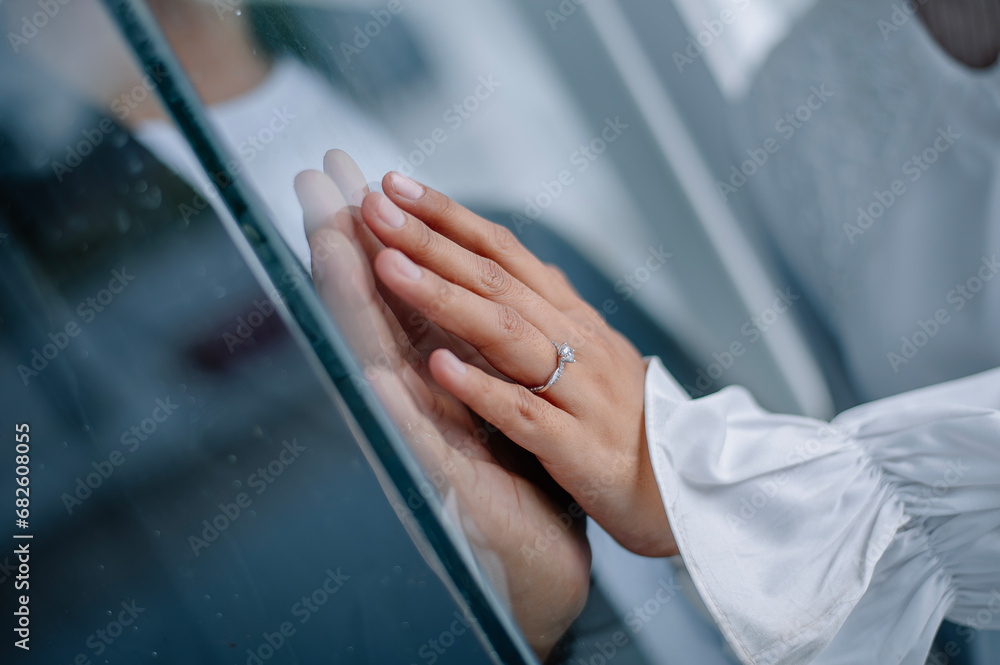 the romance of two couples' hands pressed against the glass. The woman's hand is wearing a wedding ring and a white dress, while her partner's hand is wearing a black suit