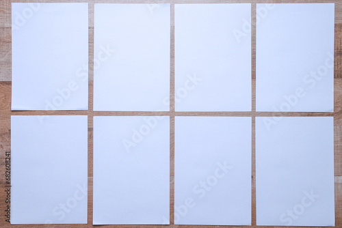 White empty papers mockups arranged on wooden background. Flat lay, top view. Open composition.