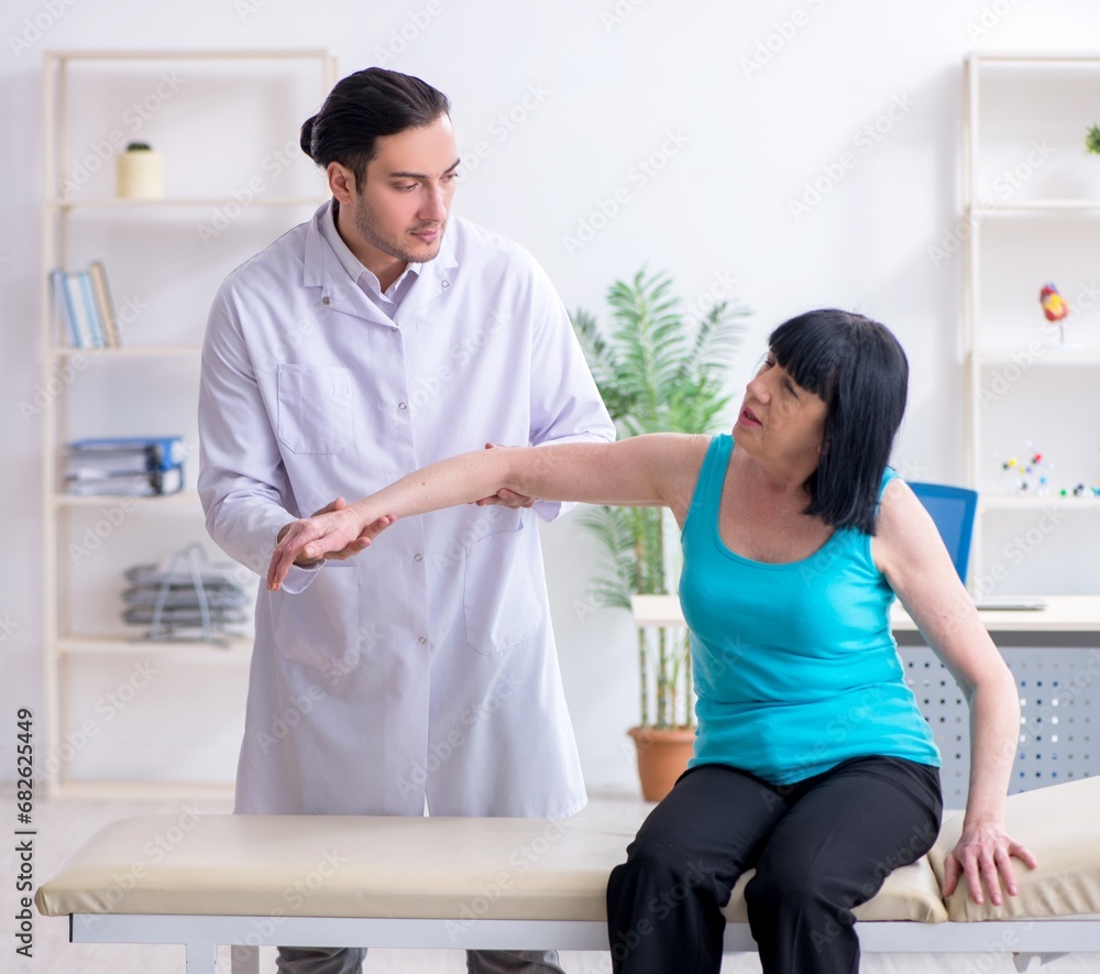 Fototapeta premium Young male doctor examining old female patient
