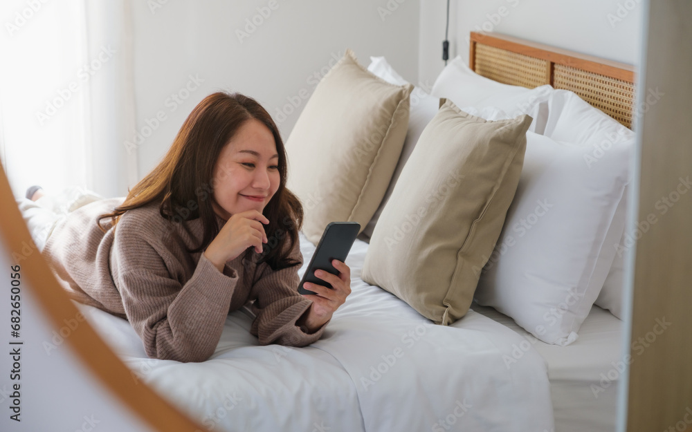 Portrait image of a young woman using mobile phone while laying on the bed Portrait image of a young woman using mobile phone while laying on the bed