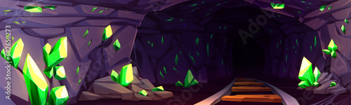 Mine cave with green precious materials in walls and railroad. Cartoon game vector of dark tunnel with rocky sides and minerals for miners to extract. Geology concept with gemstone in cavern.