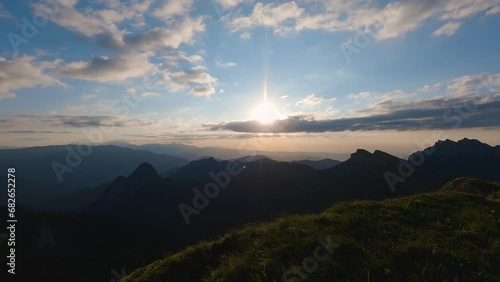 A panorama of the mountains at sunset. The sun is shining through the clouds. Black silhouettes of the mountains disappearing behind the horizon. The beauty of the wildlife photo