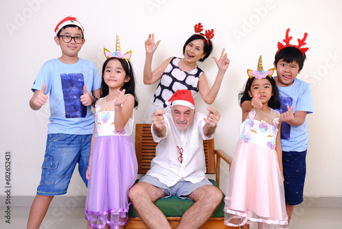 Joyful Asian grandpa and grandma getting together with their grandchildren to have their photo taken during Christmas photo