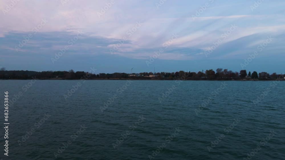 Aerial dolly push in above lake ripples and coastline with thin wispy clouds above Aerial dolly push in above lake ripples and coastline with thin wispy clouds above