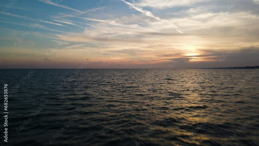 Low flying aerial dolly above ripples of ocean water as sun sets behind clouds Low flying aerial dolly above ripples of ocean water as sun sets behind clouds