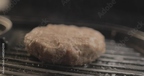 Beef or Chicken Burger on  grill being prepared for a delicious burger sandiwich , with a black background and simple light set up shot on RAW 4K photo