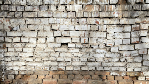 Old uneven crumbling brickwork. The texture is made of dilapidated brick. White brick wall.